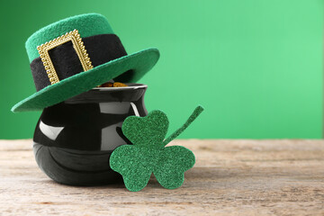 St. Patrick's day. Pot of gold with leprechaun hat and decorative clover leaf on wooden table. Space for text