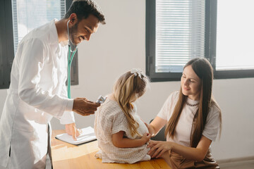 Male Pediatrician examining cute little girl with stethoscope..
