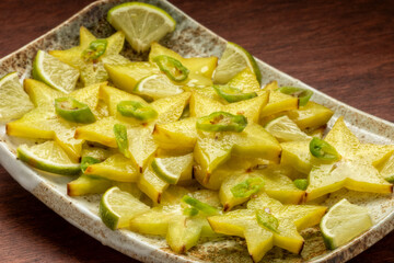 Homemade carambola or star fruit spicy salad with frozen green chili, lime pieces, and lime juice....