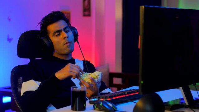 A professional Indian gamer relaxing after a long virtual playing session - leisure activity  relax  chill  refreshing. Young mature adult binge watching web series with snacks and drinks - popcorn...