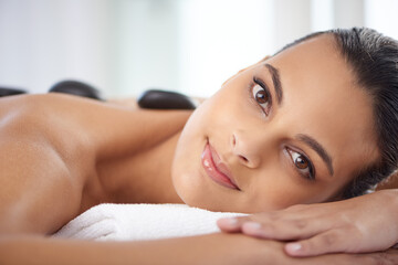 Portrait, hot stone and woman with massage for relaxing at spa for wellness, health and back...