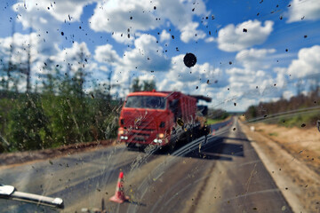 Dirty road after rain. Dirt highway with dirt flies on the windshield from other cars, dirty conditions for driver. Road repair continues