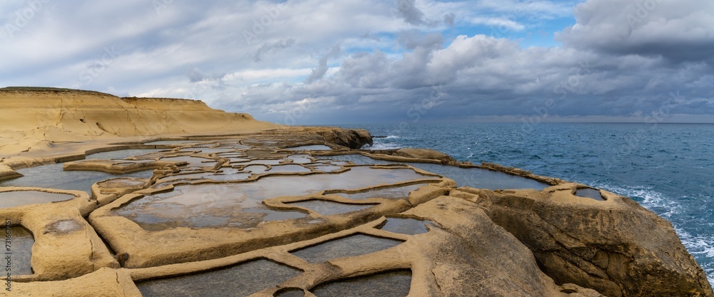 Poster panorama view of the salt pans in xwejni bay on the maltese island of gozo