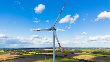 Aerial view of a modern white and red wind turbine on a rural field © Wirestock