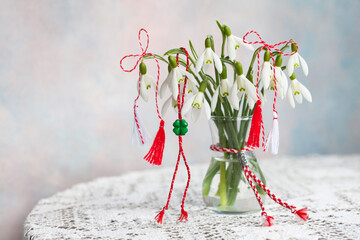 Snowdrop flowers on the table in a vase, red and white symbol of Martenitsa holiday Martisor, Baba Martha, still life, postcard
