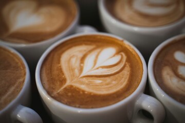 Selective focus of a cup of latte with a leaf design against the isolated background