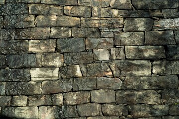 Old dark-gray wet stone building wall.