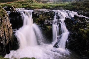 Fototapeta na wymiar Aerial long exposure shot of a waterfall surrounded by rocks