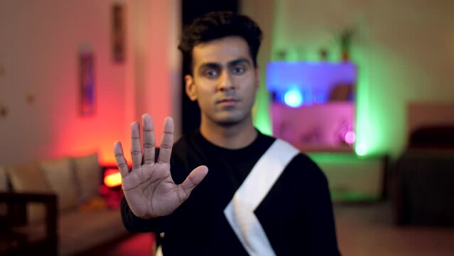 An Indian man saying no to something - refusing the offer  rejecting the plan  gesture of no  not listening. Portrait of a young man with stop sign - no action  declining the offer  disagreeing wit...