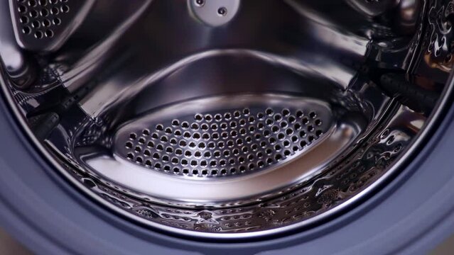 Shiny steel empty washing machine drum spinning close up