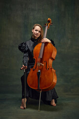 Female celloist sitting with cello on dark green background. Cover for upcoming music events, solo...