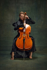 Young woman in black dress, cellist sitting on chair and playing cello against dark green background. Classic music personal therapy. Concept of classical art, retro style, music, inspiration © master1305