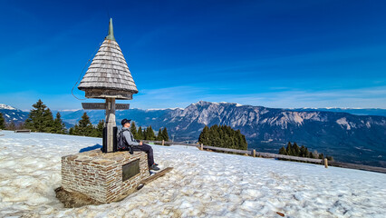 Hiker man at wooden monument at Dreilaendereck, Karawanks, Carinthia, Austria. Triangle border...
