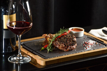 Obraz na płótnie Canvas Succulent grilled beef steak with red wine, seasonings, fresh rosemary and grilled vegetables on cutting board