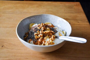 Breakfast bowl with yogurt, banana, chocolate protein, walnuts and chia seeds in a ceramic bowl