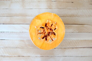 Cut pumpkin on wooden background, a half pumpkin, top view