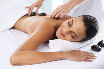 Relax, calm and woman with hot stone massage at spa for health, wellness and back treatment. Self care, sleeping and female person with warm rock skin therapy with masseuse at natural beauty salon.