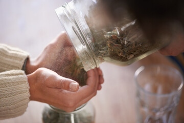 Hands, jar and tea leaves for herbal drink in kitchen for healthy benefits for beverage or...
