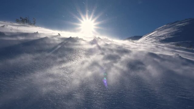 Panorama of frozen winter alps mountains with snow blown by strong wind in windy nature, low angle view