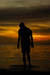 Young adult male silhouette featured in a beach setting at sunset