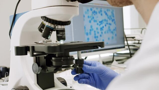 Close-up view of a person working with a microscope in the lab