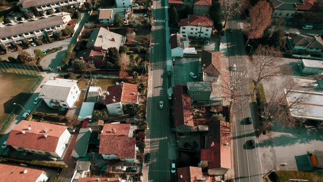 Drone footage flyover cars on city streets, squares and orange houses roofs on a sunny day