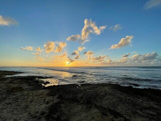 Ethereal golden sunset is seen peeking through a cloudscape over the vast horizon of the ocean