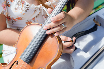 top view closeup of unrecognizable woman holding violin with one hand taking it out of case outdoors