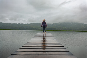 Traveler woman walks along a pier in a lagoon in the Peruvian jungle.
