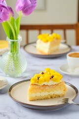 Sliced biscuit cake with cream cheese cream, lemon layer and yellow biscuit decor on a ceramic plate on a light background. Recipes for biscuit cakes.