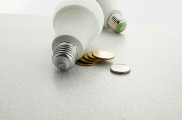 Closeup of a light bulb surrounded by banknotes and coins, concept of high electricity rates
