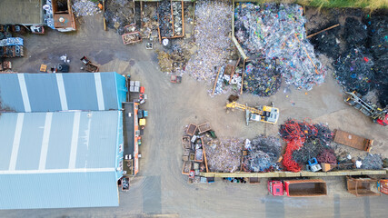 This image offers a detailed overhead look at the complex operations of a waste management facility. The scene is a mixture of order and disorder, with piles of recyclable materials segregated into