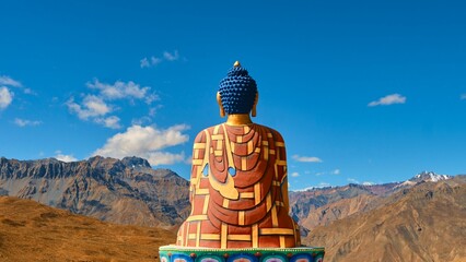 Majestic sculpture of Buddha against the stunning backdrop of a mountainous landscape.