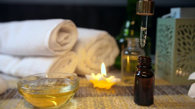 Clinically tested oil drips in the bottle from a dropper before a rejuvenating spa session . Salon expert examining the consistency of almond oil before a body massage appointment - scented wax can...