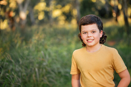 Portrait of happy boy wearing yellow shirt in Australian country bush setting