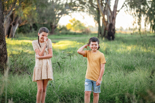 Brother and sister standing awkwardly in Australian country bush setting