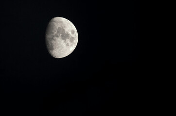 The moon in the waxing gibbous phase against a black sky at night. 