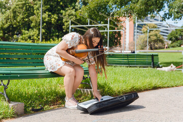 young woman violinist busker artist placing case on floor for money