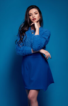 Studio fashion: gorgeous young woman dressed in blue skirt and sweater. Portrait of pretty girl