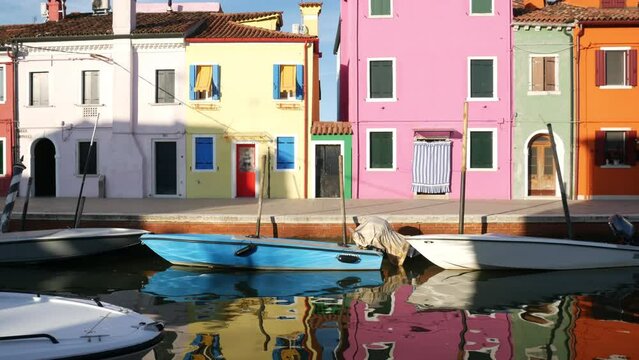 Colorful Houses are reflected in the water of the canal in Burano, Venezia island city