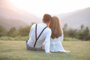 Affectionate couple enjoying a beautiful outdoor view, sitting on a lush green grassy hill
