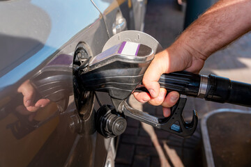 A man filling fuel tank of his car with diesel fuel at the gas station close up, as cost of fuel...