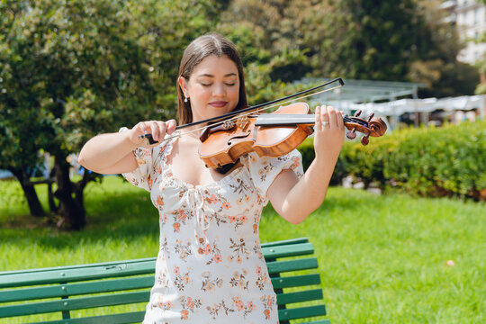 waist up portrait of happy young latin busker violinist woman playing outdoors in Buenos Aires