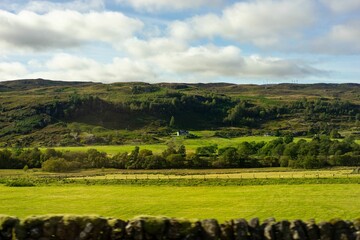 Fototapeta na wymiar Scenic landscape view of Scotland featuring rolling grassy fields, lush green trees, and mountains
