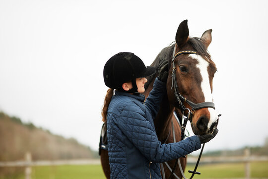 Girl standing and stroking horse