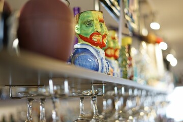 Closeup of Tiki mug on bar shelf with a two-faced man
