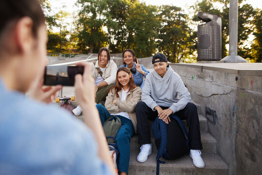 Group of friends hanging out together in skatepark and taking photos