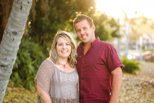 Happy twenty-something couple standing together in golden afternoon light at the park