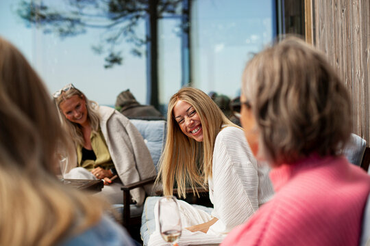 Cheerful female friends talking to each other while spending leisure time on weekend