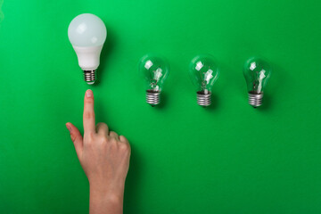 Idea male hand touch LED light bulbs on green color background. Flat lay with copy space. Concept...